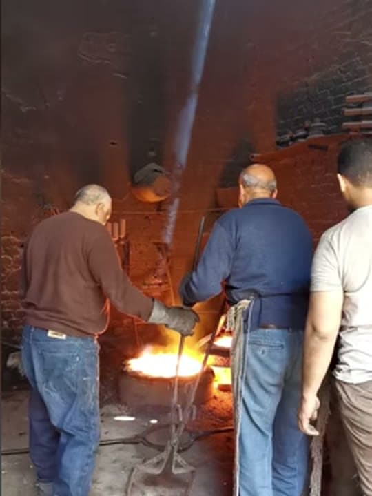 Foundry workers tending molten metal at a furnace